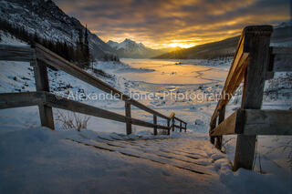 Sun rising in the mountains over frozen lake during winter at medicine lake in Jasper National park canada