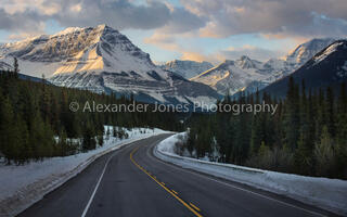large mountain looming over road during sunrise on the icefields parkway in jasper national park and banff national park