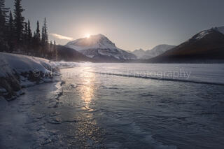 Sun rising over mountaintop on winter morning in Jasper National Park in Canadian Rocky Mountains