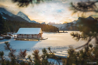 goldenhour sunrise over frozen lake and boathouse at malgine lake in jasper national park in canadian rocky mountains