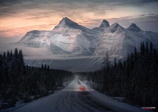 Car driving through canadian rocky mountains during sunrise in winter