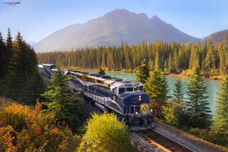 Rocky Mountaineer train in banff national park on a warm summer morning with mountains in the distance