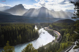 Rocky Mountaineer at morants curve in banff national park with sunny mountains in the background