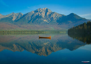 A single canoe drifting in the middle of Pyramid Lake with Pyramid Mountain in the background
