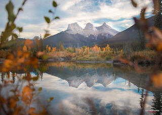 Three Sisters Mountains reflecting over a lake in Canmore Alberta Canada in the Canadian Rocky Mountains on a bright spring day