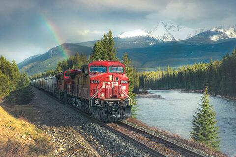 train with rainbow in background and snow capped mountains banff national park