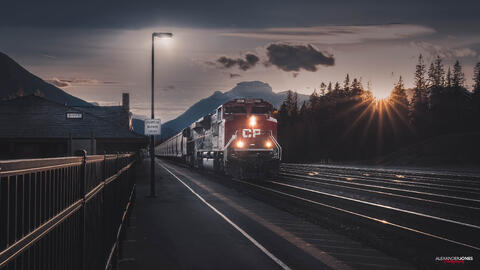 Banff train station during sunset with a train passing through the station