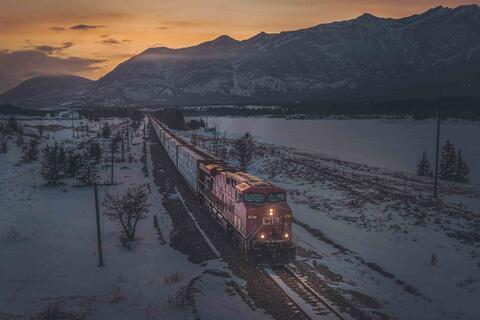 train photographed during dusk set against snow capped mountains