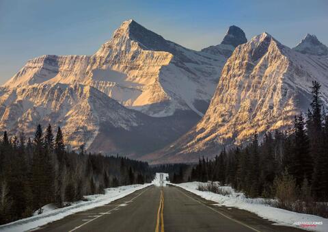large mountain looming over road during sunrise on the icefields parkway in jasper national park and banff national park