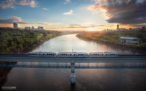 Edmonton Metro ETS train crossing bridge during sunset with city of in distance