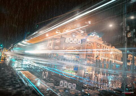 a tram long exposure passing flinders street station on a rainy night in melbourne australia