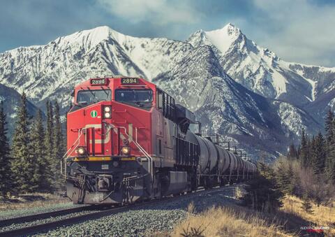Long freight train going past big snowy mountains in canadian rocky mountains