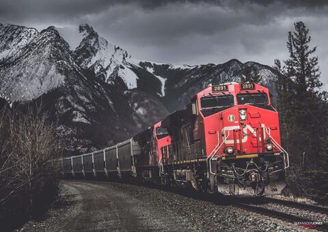 Red freight train in black and white mountains in Jasper National Park in the Canadian Rocky Mountains 