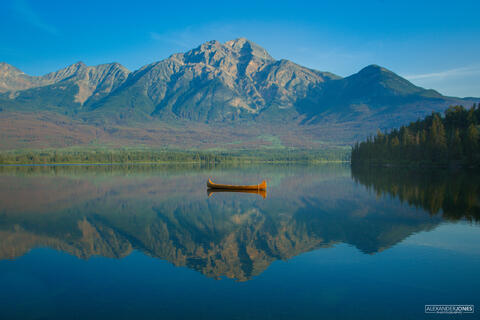A single canoe drifting in the middle of Pyramid Lake with Pyramid Mountain in the background