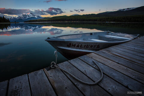 Boat sitting idle in dock during a mountain sunrise at Maligne Lake in Jasper National Park in the Canadian Rocky Mountains