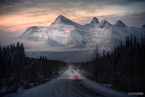 Car driving through canadian rocky mountains during sunrise in winter