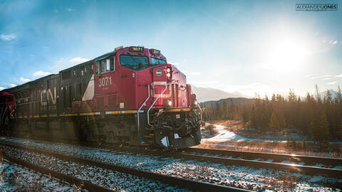 CN freight train with blue sky and sun shining in the background