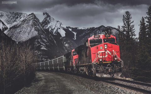 Red freight train in black and white mountains in Jasper National Park in the Canadian Rocky Mountains 