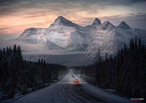 Car driving through canadian rocky mountains during sunrise in winter