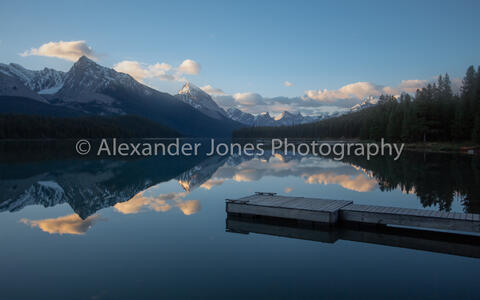 Mirror reflection during sunrise over Maligne Lake and pier in Jasper National Park in Canadian Rocky Mountains