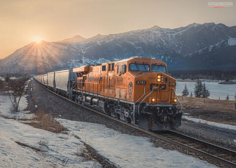 train during sunset with snow-capped mountains in the distance in the Canadian rocky mountains 