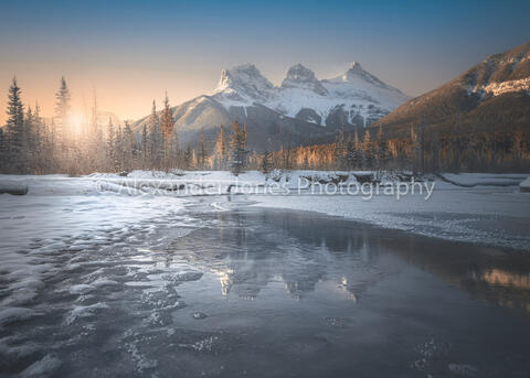 sun rising over three sisters in canmore during winter 
