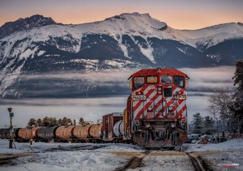 Freight train on a cold morning with mountains in distance during sunrise in Jasper National Park in Canadian Rocky Mountains Canada