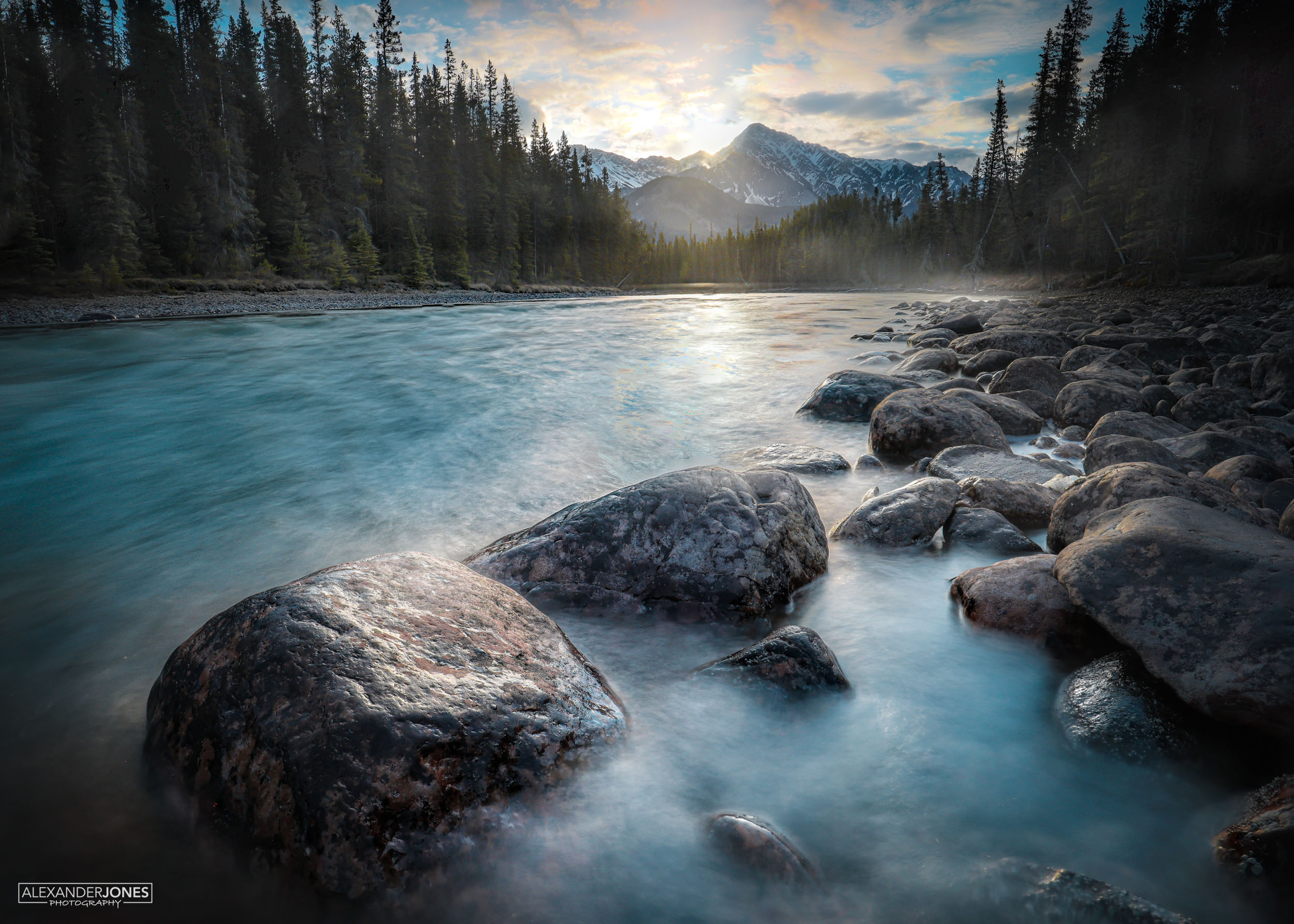 Bow River Rise sunrise over snow capped mountains onto athabasca river rocks in banff national park in canadian rocky mountains