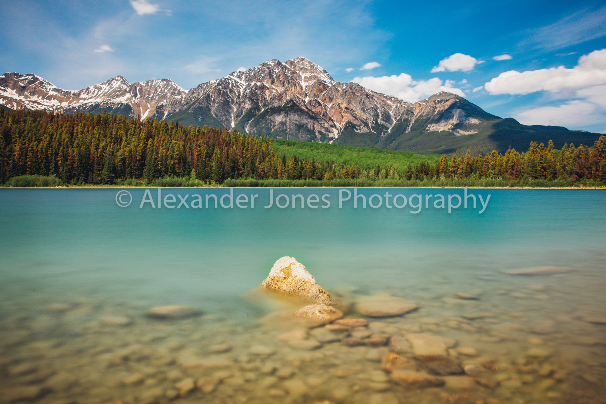 Pyramid Rock Jasper bright summer lake with snow capped mountains in canadian rocky mountains in jasper national park