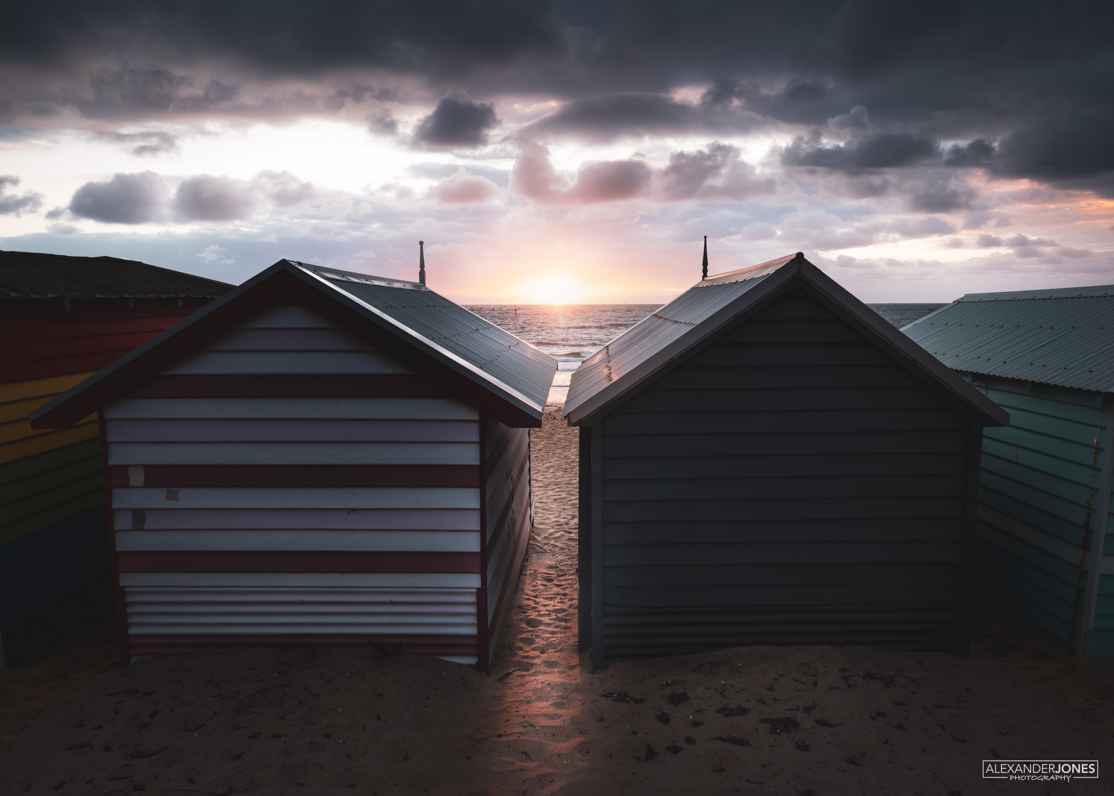 Sun setting over the horizon behind the world famous brighton bathing boxes at brighton beach in melbourne australia
