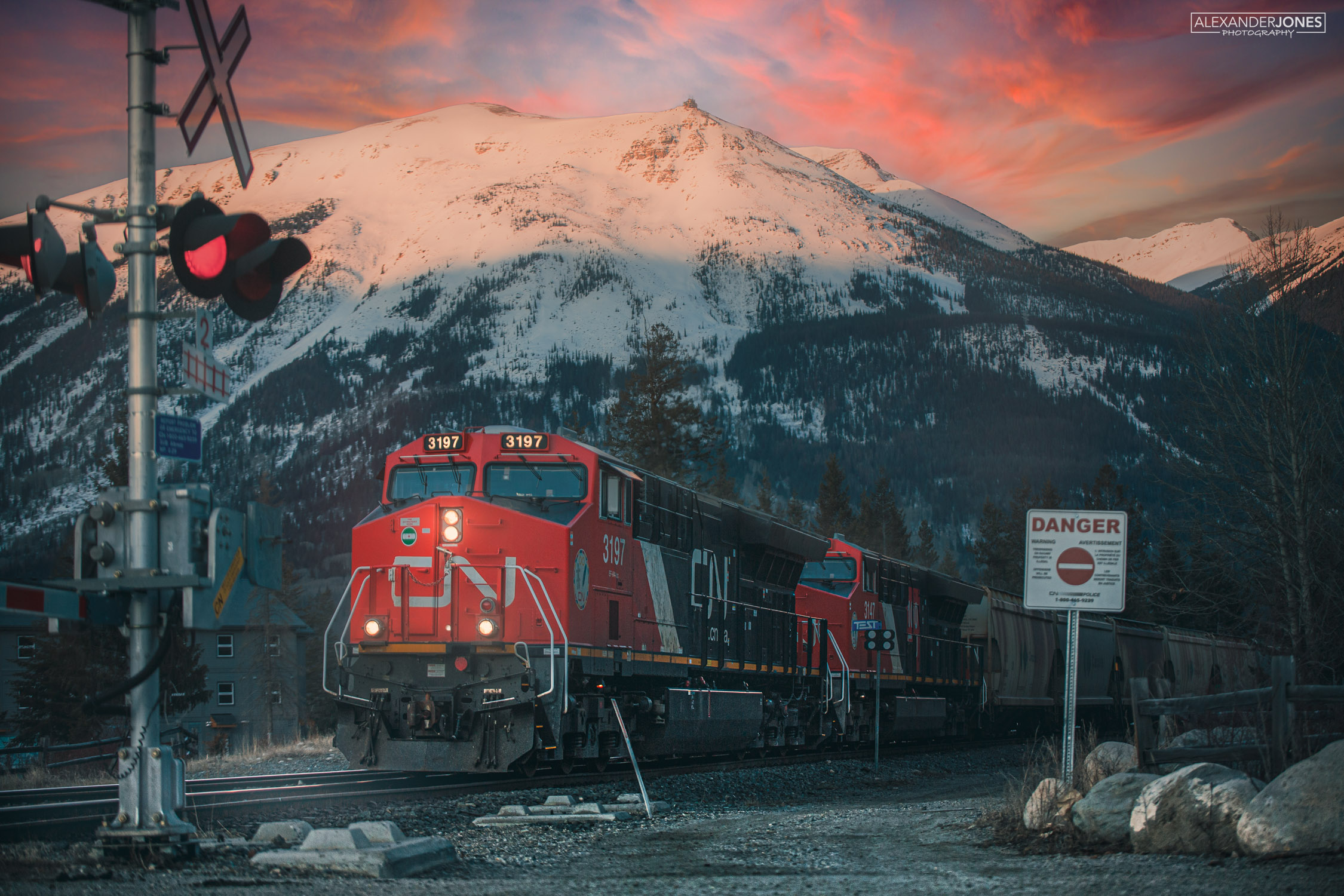 A CN train during sunrise in front of a snowcapped Whitstler's Mountain and the Jasper Skytram in Jasper National Park on a summer morning.