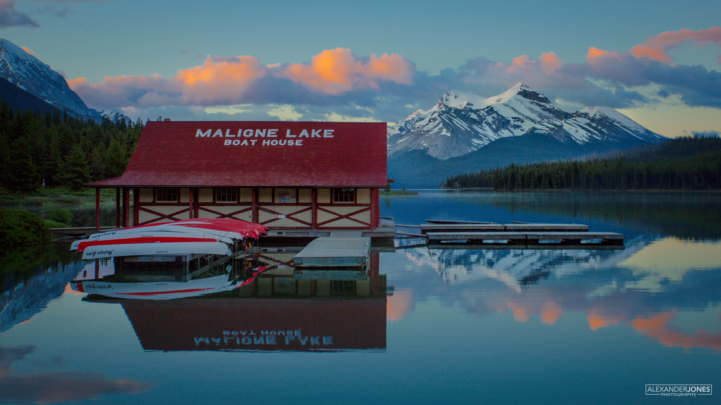 Maligne Glimmer Jasper Sun rising over Maligne Lake mountains and boathouse in Jasper National Park in Canadian Rocky Mountains