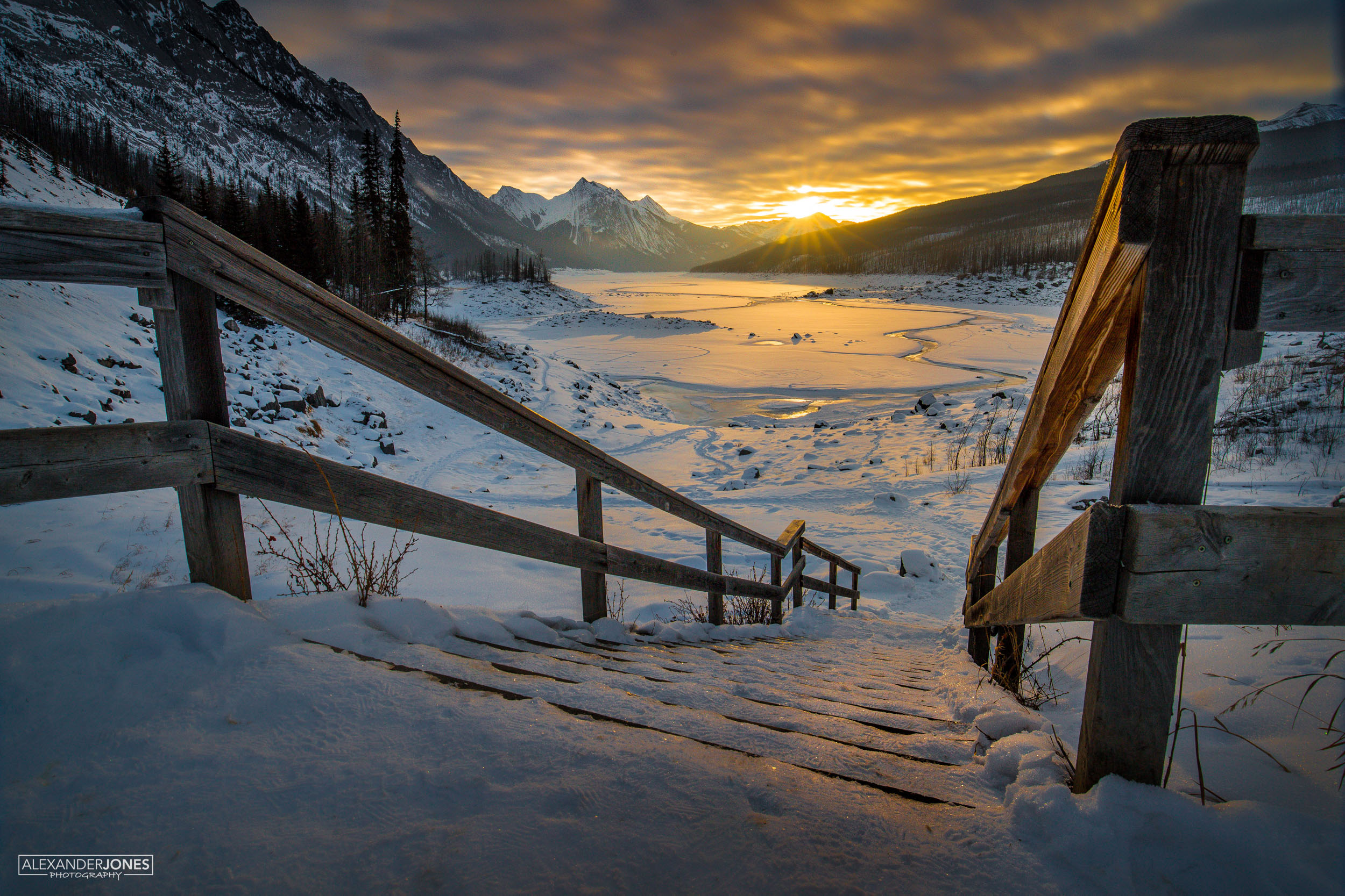 Sun rising in the mountains over frozen lake during winter at medicine lake in Jasper National park canada