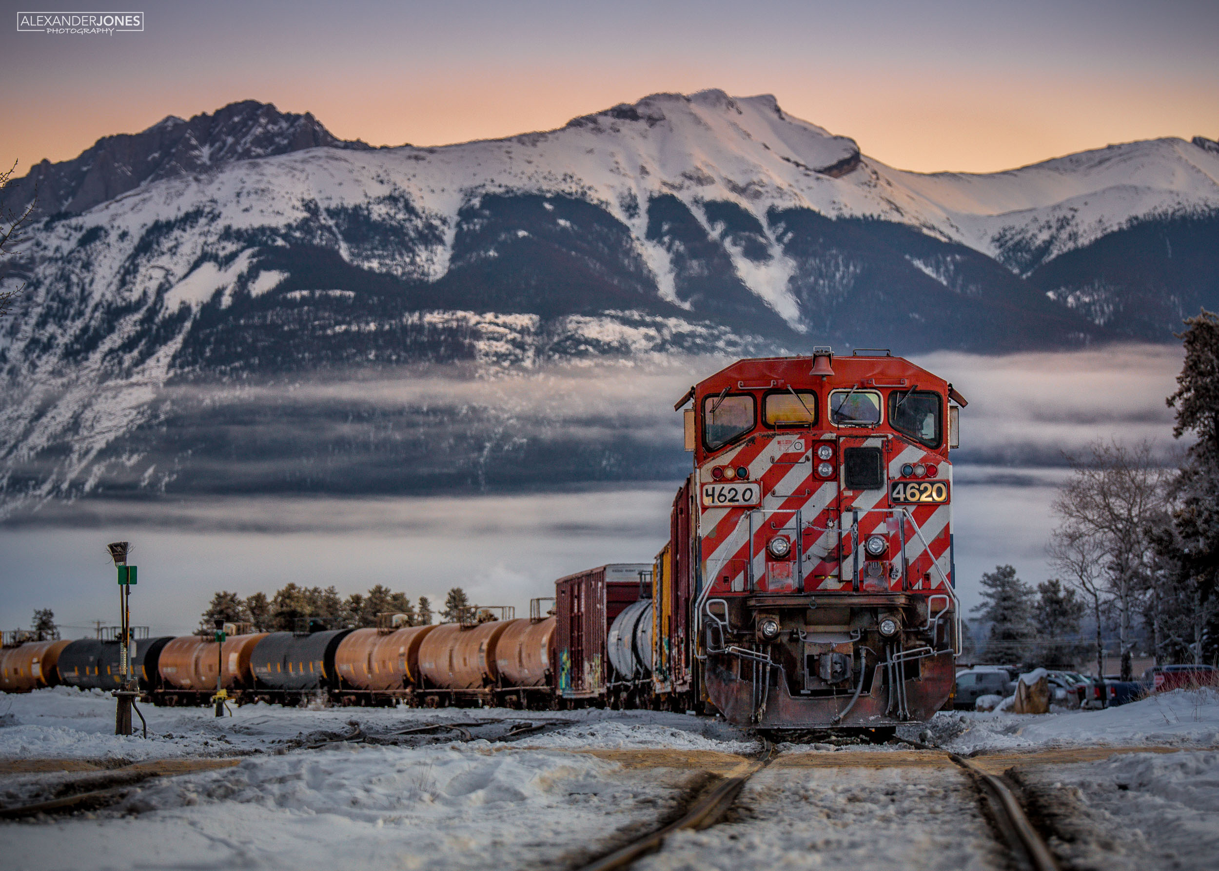 Freight train on a cold morning with mountains in distance during sunrise in Jasper National Park in Canadian Rocky Mountains Canada